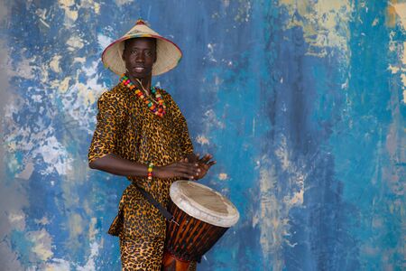 African man in traditional clothes playing djembe drumの写真素材