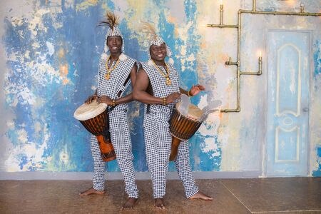A group of people in traditional african costumes playing jembe drumsの写真素材