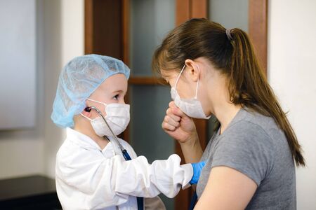 Small boy playing doctor and patient with his mother wearing a stethoscope.の写真素材