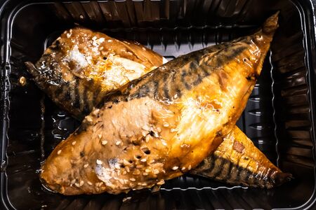 cooked headless mackerel in a black plastic containerの写真素材