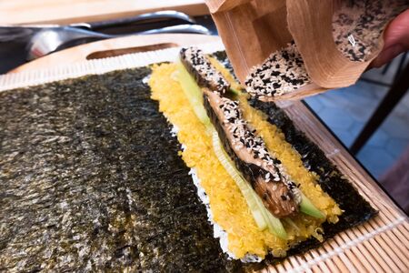 bamboo rolling mat for homemade sushi with nori, ricota, quinoa, cucumber, mackerel sprinkle with sesame seedsの写真素材