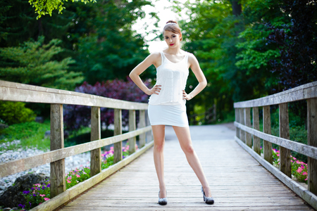 Beautiful girl is in on a wooden bridge. Casual and thoughtful in a park during summer.の写真素材