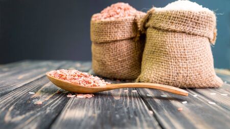 Brown rice in wooden spoon, Brown and white rice in bag on woodenの写真素材