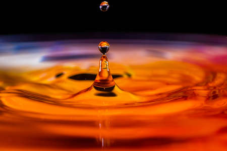 Close up of a water drop falling and impacting on a body of waterの写真素材