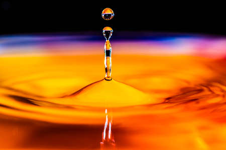 Close up of a water drop falling and impacting on a body of waterの写真素材