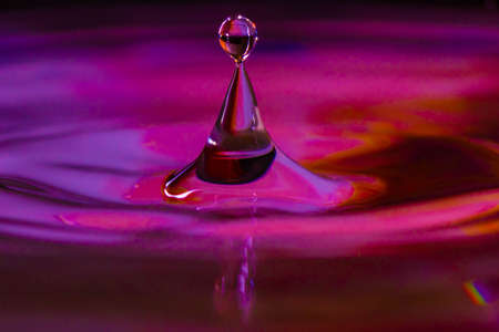 Close up of a water drop falling and impacting on a body of waterの写真素材