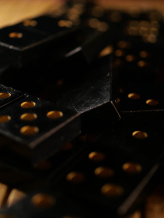 Black vintage dominoes on a black background, selective focus. WB photo.