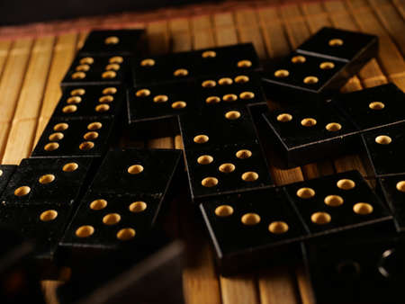 Black vintage dominoes on a black background, selective focus. WB photo.