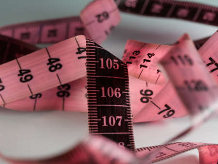 Close up tailor measuring tape on white table background. White measuring tape shallow depth of field. Macro.の写真素材