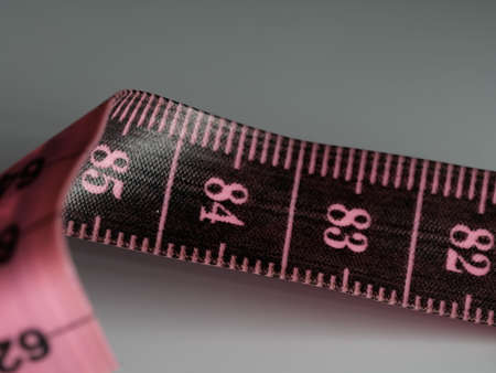 Close up tailor measuring tape on white table background. White measuring tape shallow depth of field. Macro.の写真素材