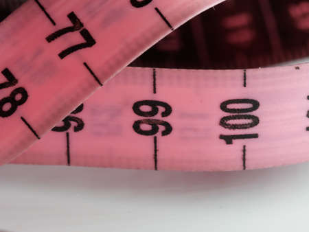 Close up tailor measuring tape on white table background. White measuring tape shallow depth of field. Macro.の写真素材