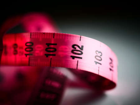 Close up tailor measuring tape on white table background. White measuring tape shallow depth of field. Macro.の写真素材