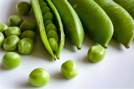 A white plate with pea pods and peas