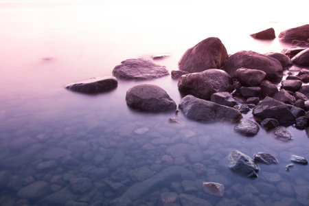 Long exposure photo of stones in calm ocean waterの写真素材