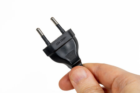 Isolated closeup of an electric plug being held in a hand