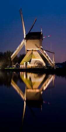 Single windmill shot at night with reflection in the waterの写真素材