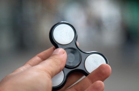 young playing with a fidget spinner, focus on spinnerの写真素材