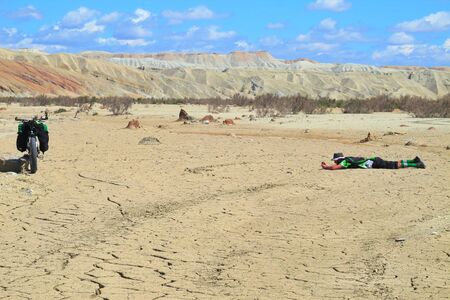 Photographer lies on the sand taking a picture of the bikeの写真素材
