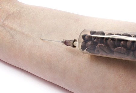 Morning dosage of coffee.A syringe with coffee beans just before the injection.の写真素材