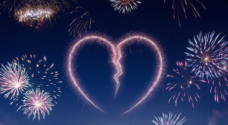 A dark night sky with a sparkling red firecracker in the shape of a broken heart composed into.(series)の写真素材