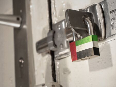 A bolted door secured by a padlock with the national flag of United Arab Emirates on it.(series)の写真素材
