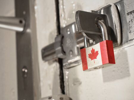 A bolted door secured by a padlock with the national flag of Canada on it.(series)の素材 [FY310143510326]