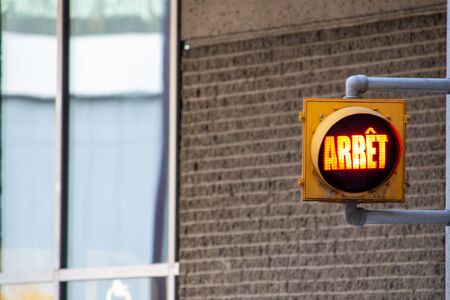 A French-language traffic light on the side of a building illuminates the word "ArrÃªt", meaning "Stop".の写真素材