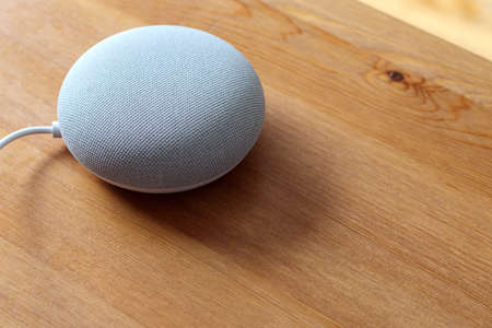 A Google Nest Mini smart speaker sits on a wooden table