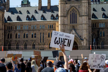 A protest sign reading "If not now, when" is held up in a crowd as thousands on Parliament Hill in Ottawa, Canada protesting police violence and racism.のeditorial素材