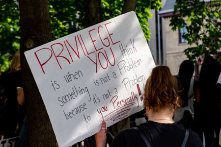 A woman holds a sign about white privilege as thousands gather in downtown Ottawa, Canada to protest police violence and racism following the American killing of George Floyd.のeditorial素材