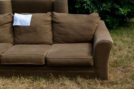 A couch sits on the grass of a front lawn beside the road with the word "free" written on it.の写真素材