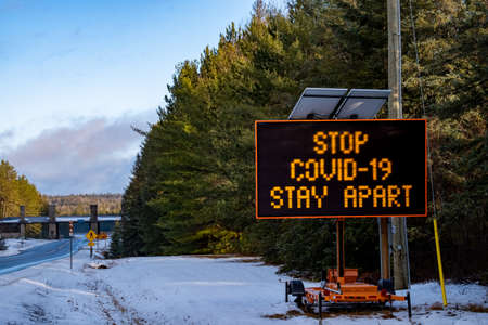 Algonquin Provincial Park, Ontario, Canada - November 28, 2020: A portable electronic message board trailer at the East Gate to Algonquin Provincial Park reads "STOP COVID-19, STAY APART".のeditorial素材