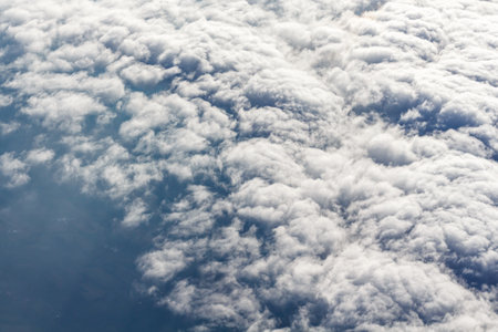 An aerial view above cloud cover shows the texture of the clouds.