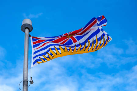 Low-angle view of the flag of the Canadian province of British Columbia (BC) on a flagpole.の写真素材