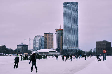 Ottawa, Ontario, Canada - January 22, 2022: Ice skaters enjoy the Rideau Canal Skateway at Dow's Lake. The Dows Lake Pavillion and condominiums, including the Claridge Icon, stand in the background.のeditorial素材