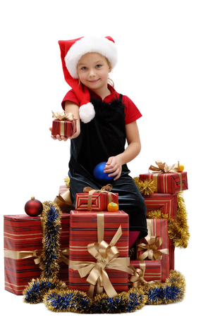 Cute little girl in a Santa Claus cap with Christmas gifts on a white background, isolatedの写真素材