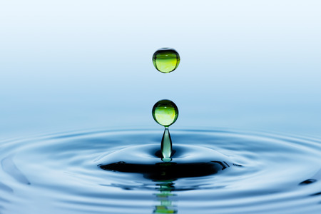 Splash. Round green drops falling on smooth surface of water.の写真素材