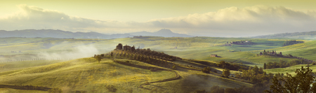 Panorama, Italian beautiful landscape, foggy rolling fields of Tuscany in light of the rising sunの写真素材