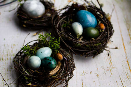 three Easter nests with Easter eggs on a wooden background