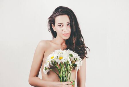 tender cute beautiful summer young girl with topless body perfect skin. holds camomiles flowers. white backgroundの写真素材