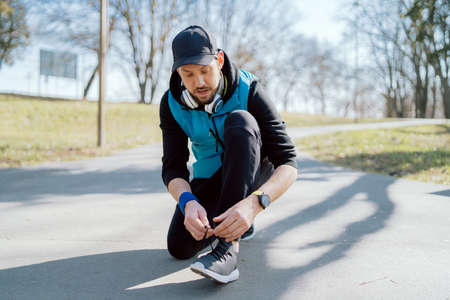 A man tying his running shoes. A person running outside on a sunny spring day. Two hands reaching...