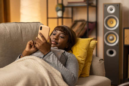On the couch lies a happy girl who has managed to book a seat at the cinema online. The woman wants...