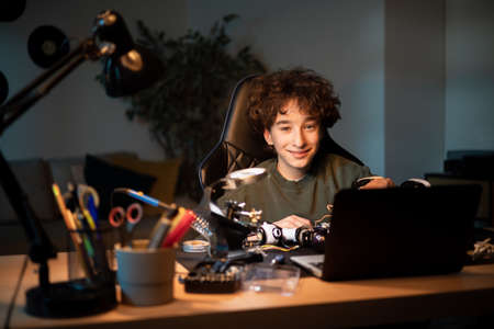 A boy works to create a fully functional robot from scratch. A clever teen solders cables at his desk, repairing the wiring of electronic equipment.の写真素材