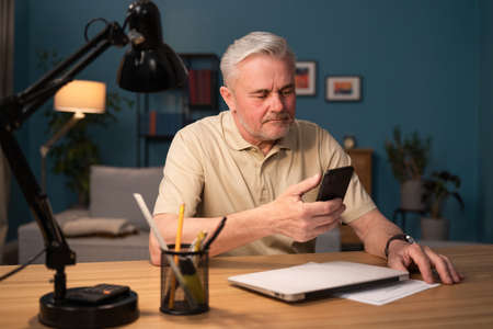 An elderly man gets acquainted with his new smartphone. A grandfather calls his grandchildren and...