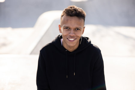 Portrait of a black man with dark hair and eyes looking ahead with a smiling, happy, kind face at...