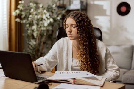 Beautiful, attractive young mother, sitting in an office chair to relax, reads the list of documents needed to register a child for schoolの写真素材