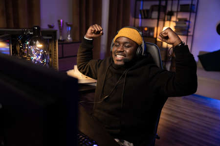 A professional player with a headset playing and winning a video game on his computer. Online...