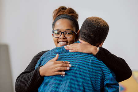 Man hugs his girlfriend, wife, lifts up with happiness, shot of legs in background of apartment with cardboard boxes, couple moves into new houseの写真素材