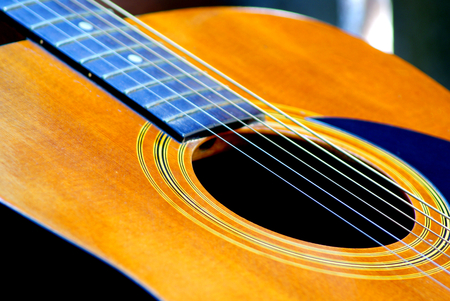 Selective focus picture parts of acoustics guitar resting in garden background with soft light in...