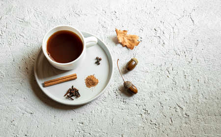 Cup of acorn coffee with cloves, cinnamon, nutmeg and black pepper on a gray background. Substitute to coffee, a healthy homemade eco-friendly hot drink. Health and no caffeine concept.の写真素材